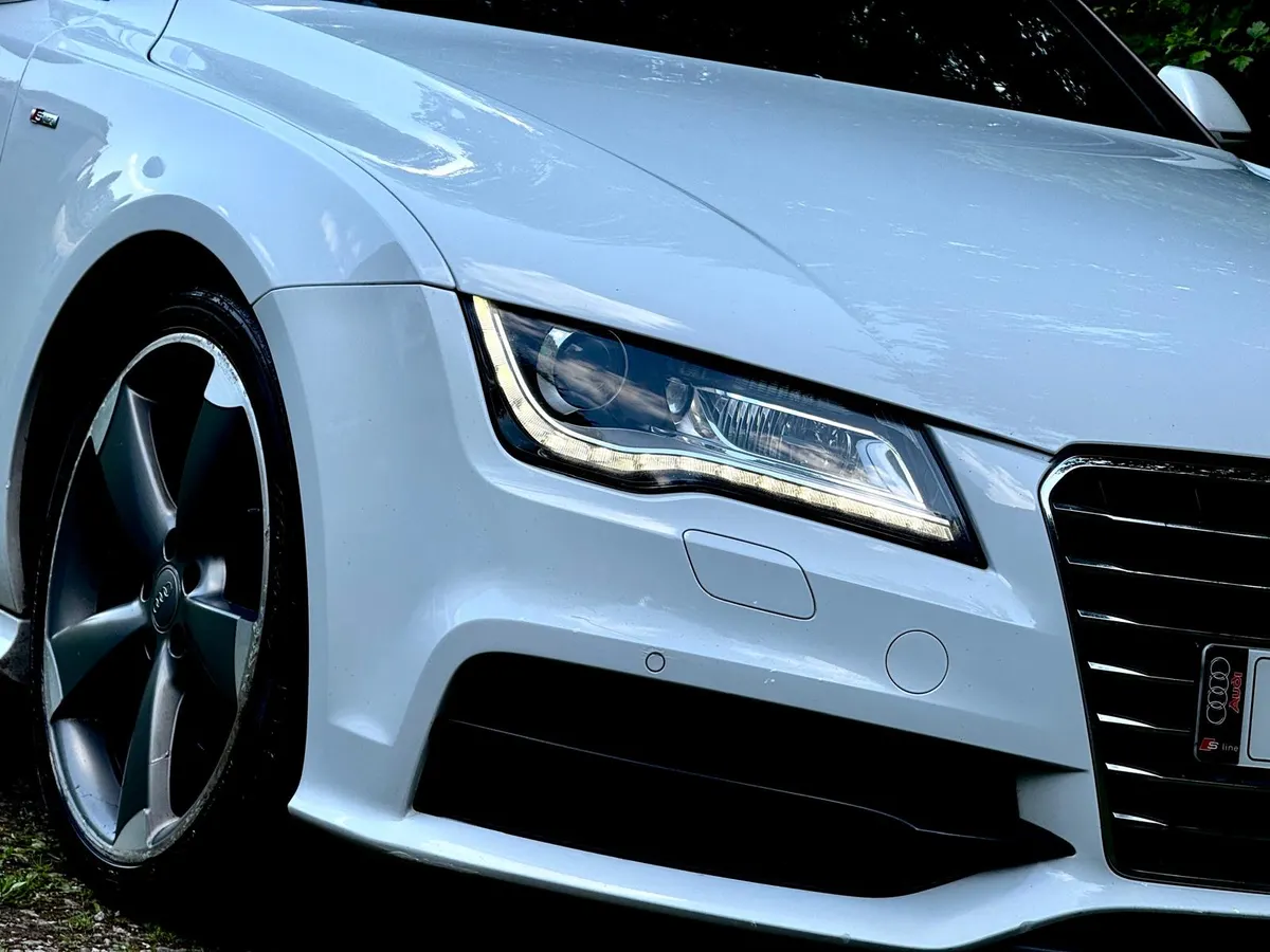 Close-up of an Audi A7 headlight and clean white paintwork