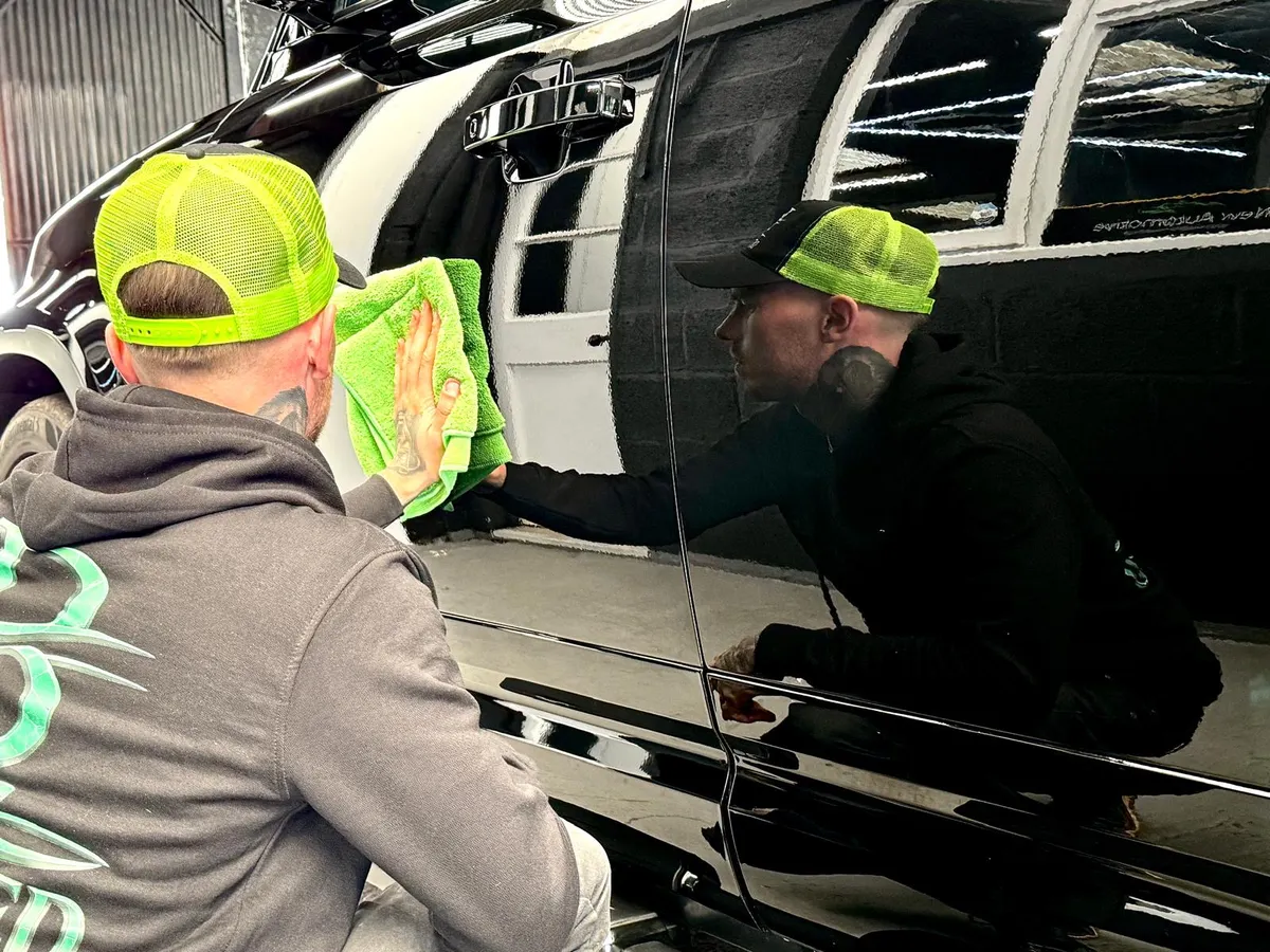Brad wiping a Defender's paint with a microfibre cloth, reflected in the finish